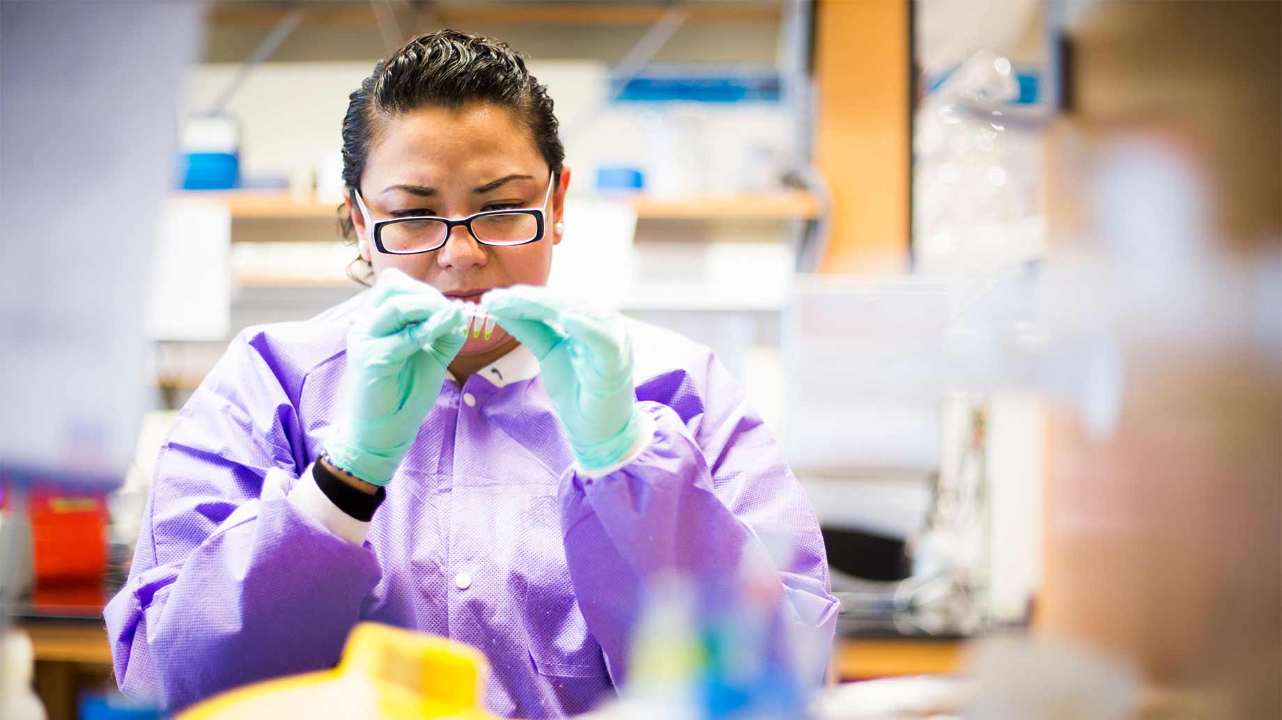 researcher in protective clothing examines samples in a laboratory