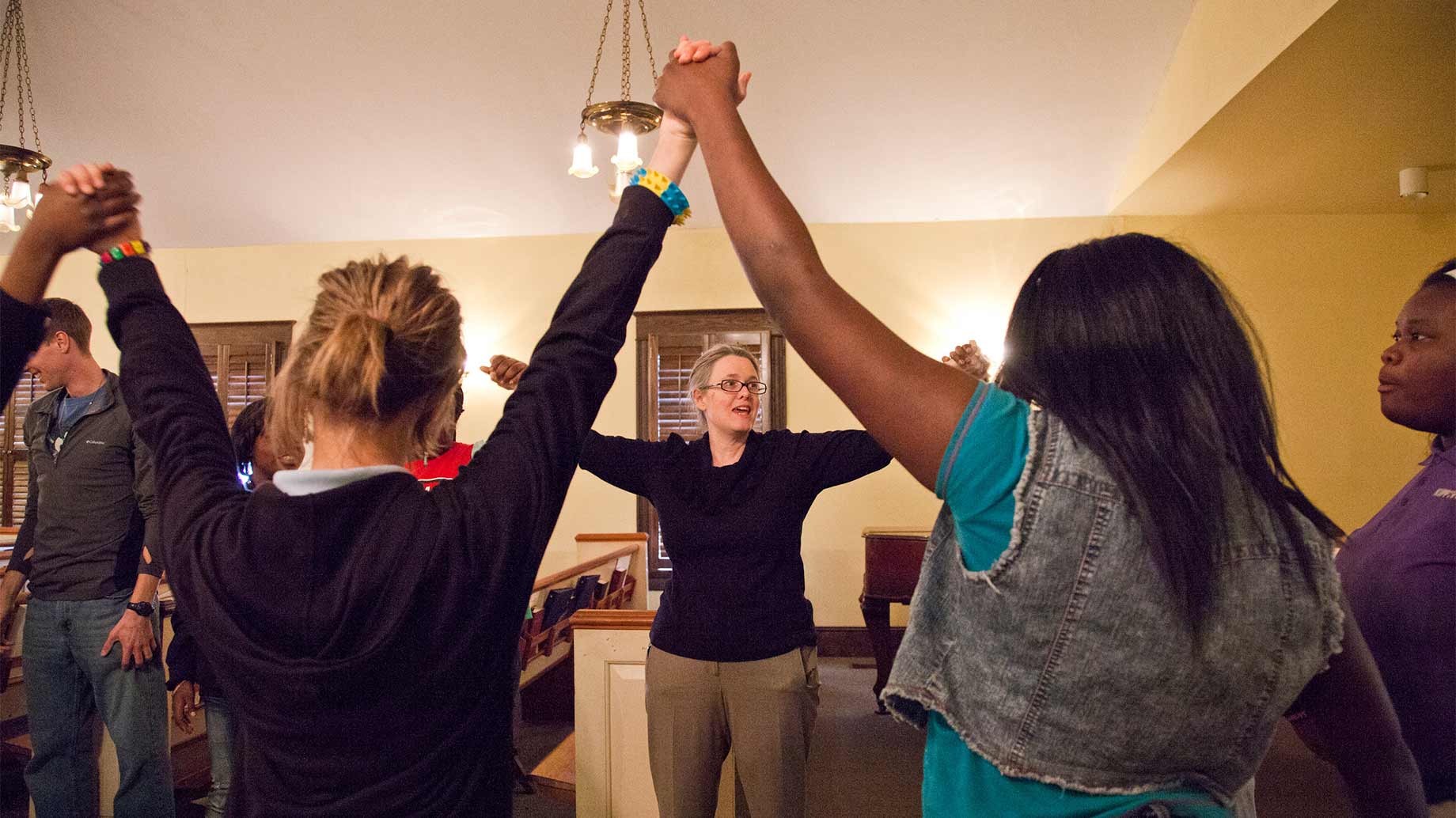 diverse group of people holding hands in a chapel