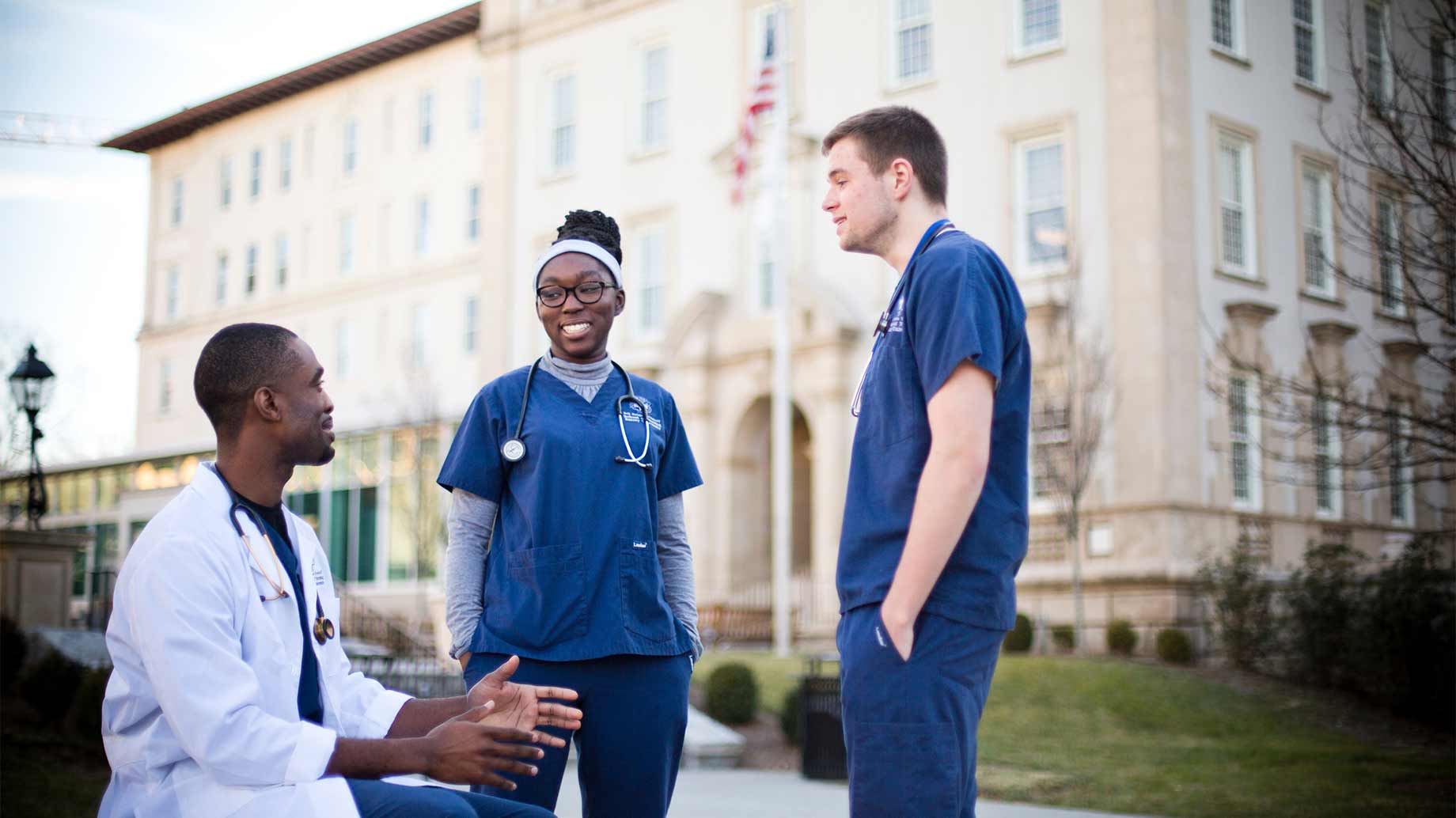 two nursing students and a medical student chatting in front of a medical school building