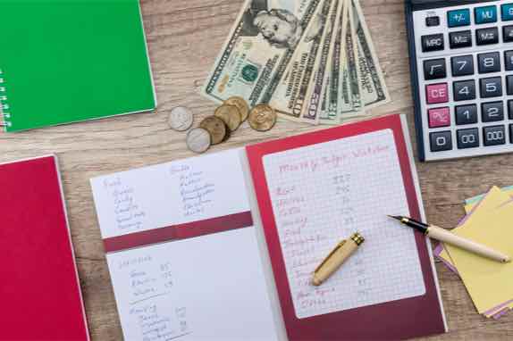 budget notebooks with cash, coins, and calculator in background