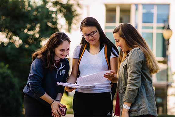 three young women looking over some paperwork outside